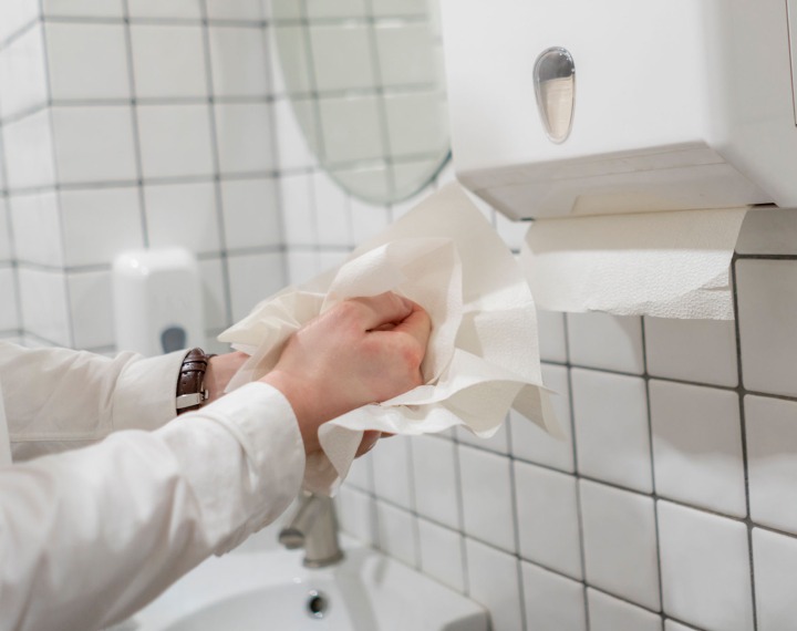 Paper hand towels being pulled from dispenser