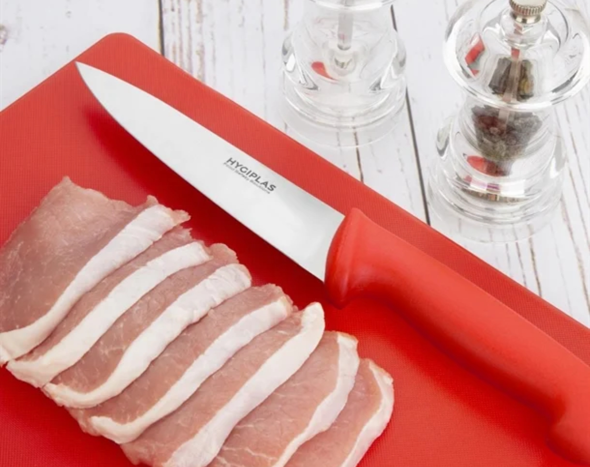 Raw meat on a red chopping board with red knife