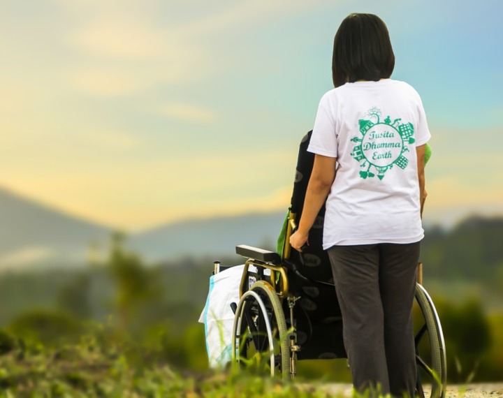Carer pushing senior in wheelchair