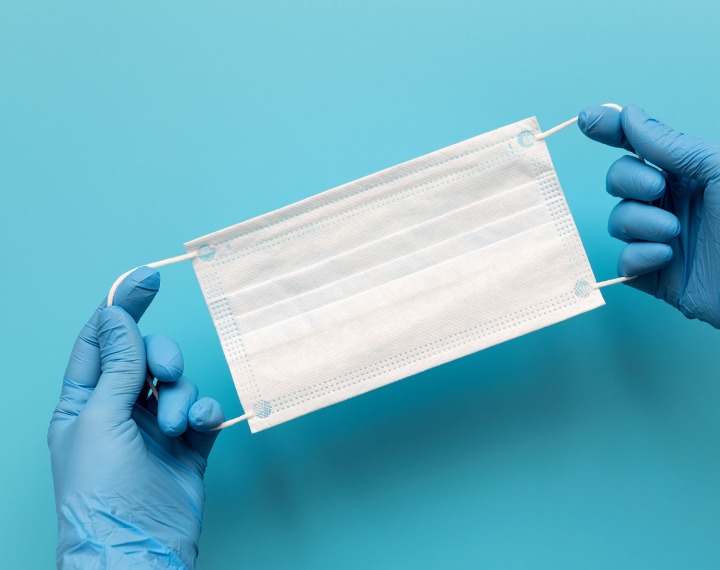 Gloved hands holding a face mask