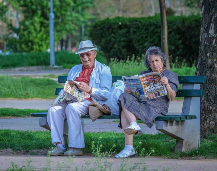 Seniors sat on wooden bench outdoors